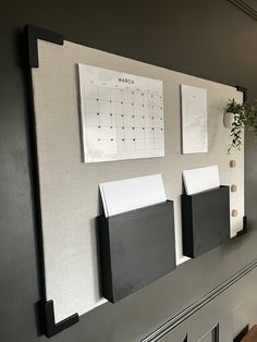 a wall mounted calendar on the side of a gray wall with black and white accents