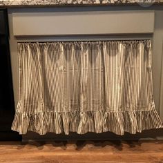 a kitchen window with a striped valance hanging from it's side, in front of an oven