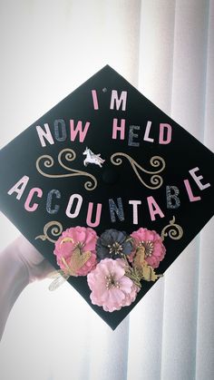 a graduation cap that says i'm now held accountable with flowers on it