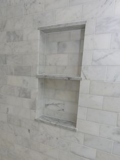 a bathroom with white marble walls and shelves