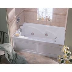 a bathroom with a bathtub and flowers in the corner