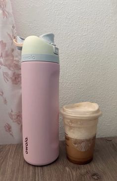 a coffee cup next to a pink insulated travel mug