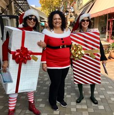 three women dressed up as santa clause and mrs peppermink holding presents in their hands