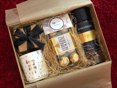 a gift box with coffee, tea and cookies in it on a red carpeted floor