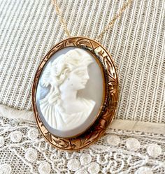 "This lovely antique, gray and white shell cameo, still a brooch, also has a \"no show\" bail that I installed. If the chain is removed, it can then be worn as a brooch. The brooch itself measures 1 1/2\" by 1 1/8\". The engraving around the rim of the bezel is beautiful. I do not know the gold content of this piece. Nor am I a cameo expert. Please check the pictures closely. The gold plated chain is 18\" long. I work with antique and vintage parts. Some may show signs of wear or age. Please loo Victorian White Cabochon Brooches, White Victorian Cabochon Brooches, Antique Cameo Medallion Brooch, Antique Cameo Medallion Brooches, Antique Oval Necklace With Brooch, Antique White Hallmarked Necklaces, Antique White Hallmarked Necklace, White Antique Hallmarked Necklace, Victorian Cameo Round Jewelry