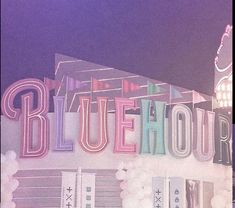 the blue hour sign is lit up in pink and white balloons on top of it