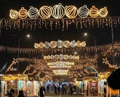 people are walking down the street decorated with christmas lights