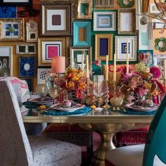 a dining room table set with place settings and colorful pictures on the wall behind it