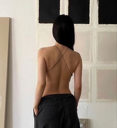 a woman standing in front of a white wall with her back turned to the camera