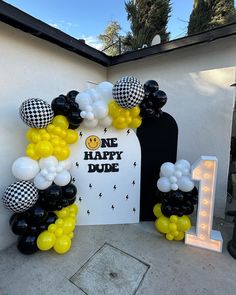 an arch made out of balloons with the number one on it is decorated in black, white and yellow