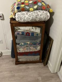 a stack of quilts sitting on top of a wooden stand next to a door