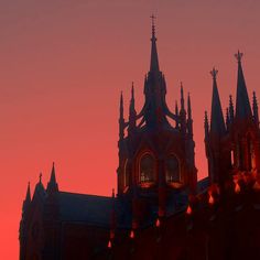 the silhouette of an old building with spires against a pink sky at sunset or dawn