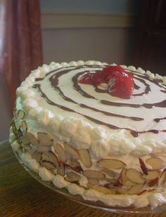 there is a cake with white frosting and a strawberry on top, sitting on a table