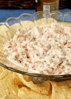 a glass bowl filled with white dip surrounded by tortilla chips