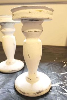 two white candlesticks sitting on top of a table