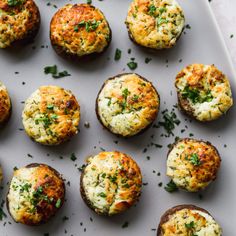 an overhead view of baked potatoes with cheese and herbs on a white platter, ready to be eaten