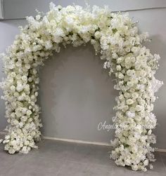 white flowers are arranged in an arch on the floor