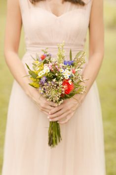 a woman wearing a dress holding a bouquet of flowers in her hands and looking at the camera