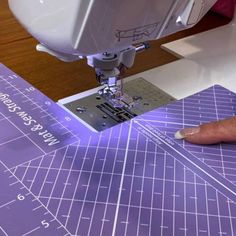 someone is using a sewing machine to sew on the purple cutting mat that they are working on