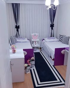 two beds in a small room with purple and white decor on the walls, along with a rug