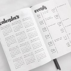 an open calendar book with black numbers on the page and pen in front of it