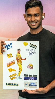 a man holding up a poster with some stickers on it's back side