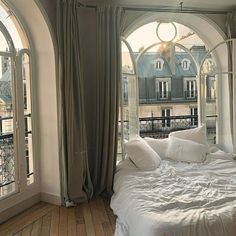 a bedroom with arched windows and white bedding