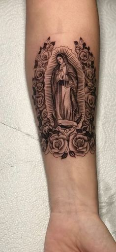 a woman's arm with a tattoo on it and an image of the virgin mary