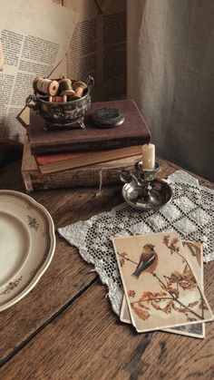 a table topped with books and plates on top of a wooden table next to a candle