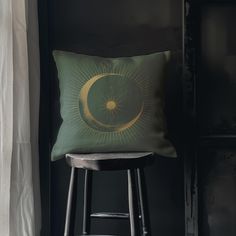 a green pillow sitting on top of a wooden stool in front of a white curtain