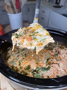 a spoon full of food is being lifted from the crock pot to be eaten