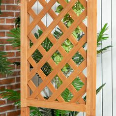 a wooden trellis on the side of a brick wall next to a potted plant