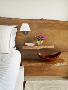 a bed with a wooden headboard and two shelves on the wall next to it