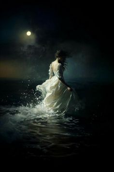 a woman in a white dress is standing in the water at night under a full moon