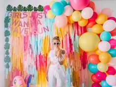 a woman standing in front of balloons and streamers