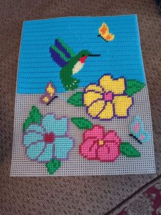 a piece of art made out of legos with flowers and a bird on it