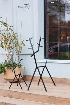 two metal sculptures sitting next to each other on top of a wooden step near a potted plant