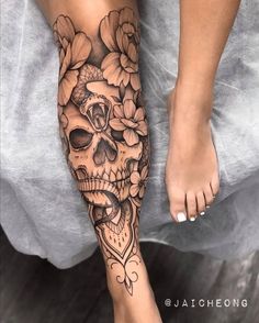 a woman's foot with a skull and flowers tattoo on the side of her leg