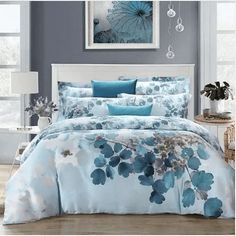 a bed with blue and white comforters in front of a painting on the wall