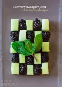 a white plate topped with fruit and green leafy garnish on top of it