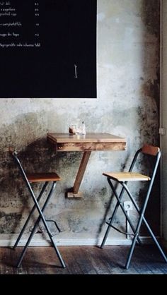 two chairs and a table in front of a chalkboard