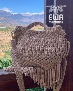 a crocheted purse sitting on top of a wooden bench next to a sign