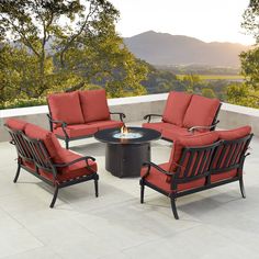 an outdoor conversation set with red cushions on a patio overlooking the trees and mountains in the distance