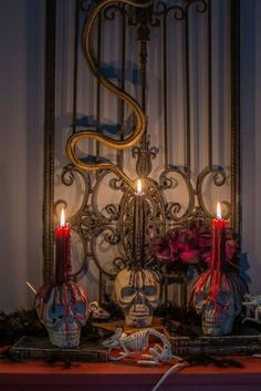 two candles are lit in front of a skeleton head and other decorations on a table