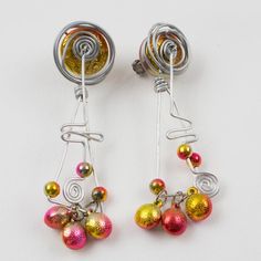 Those impressive 1990s Space Age oversized aluminum dangling clip-on earrings feature a stunning hand-made futuristic design with a dangle articulated spiral coil and geometric elements along with assorted size beads. The iridescent hot pink and yellow-orange color beads embellish the silver metal framing. There is no visible maker's mark. Measurements: 1.19 in wide (3 cm) x 4.57 in long (11.6 cm).  Please see the measurements noted above in the description for the best approximate dimensions. Space Age Jewelry, Multicolor Metal Clip-on Earrings, Unique Metal Clip-on Earrings, Futuristic Jewelry, Geometric Elements, Color Beads, Futuristic Design, Maker's Mark, Accessories Jewelry Earrings