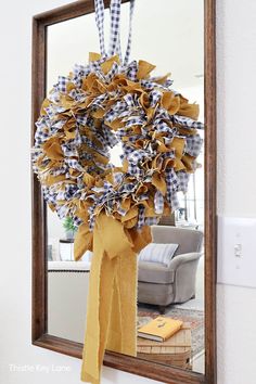 a wreath hanging on the wall in front of a mirror that is decorated with gingham fabric