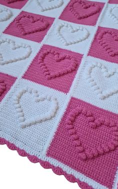 a pink and white crocheted blanket with hearts