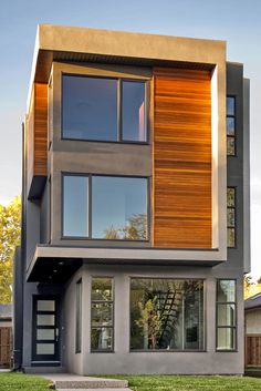 a two story house with wood and glass on the top floor, along with lots of windows