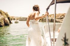 a woman in a wedding dress standing on the back of a boat