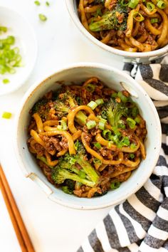 two bowls filled with noodles and broccoli next to chopsticks